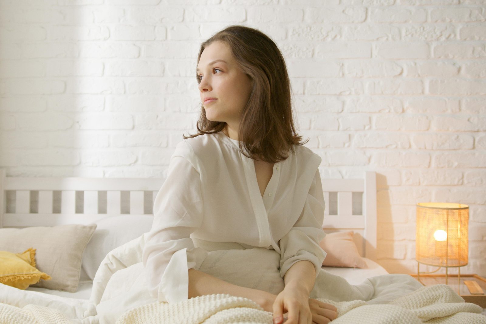 Persona sentada en la cama por la mañana reflexionando sobre errores comunes al dormir que afectan al descanso